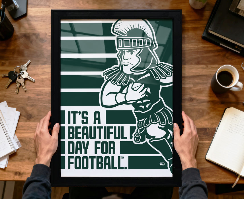 A framed poster with a cartoon illustration of a person in a football uniform, holding a football, is being held by a person's hands.