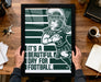A framed poster with a cartoon illustration of a person in a football uniform, holding a football, is being held by a person's hands.
