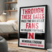 A framed poster with text that reads "THROUGH THESE GATES PASS THE GREATEST FANS IN COLLEGE FOOTBALL. N MEMORIAL STADIUM UNIVERSITY OF NEBRASKA LINCOLN"