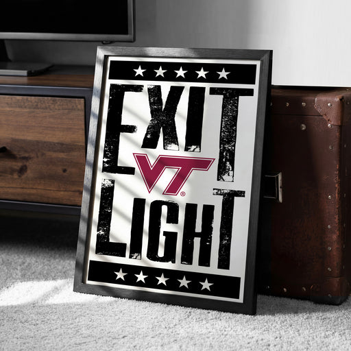 A framed poster with the text "EXIT LIGHT" and a Virginia Tech logo, placed on a carpeted floor next to a wooden chest.
