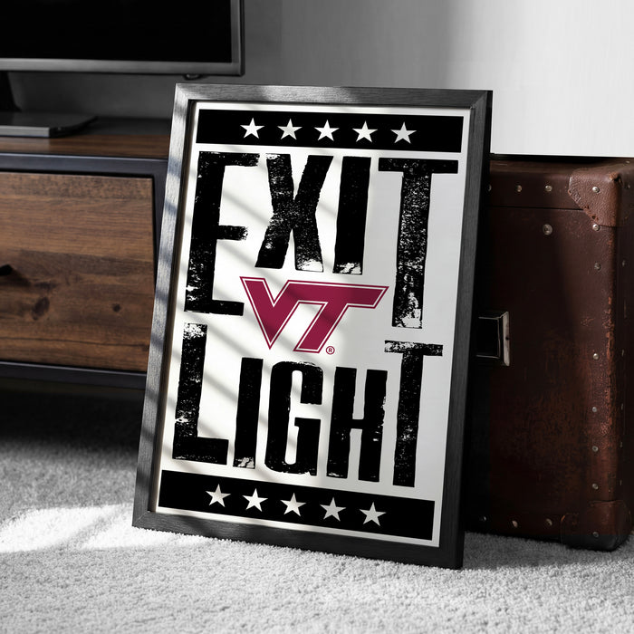 A framed poster with the text "EXIT LIGHT" and a Virginia Tech logo, placed on a carpeted floor next to a wooden chest.