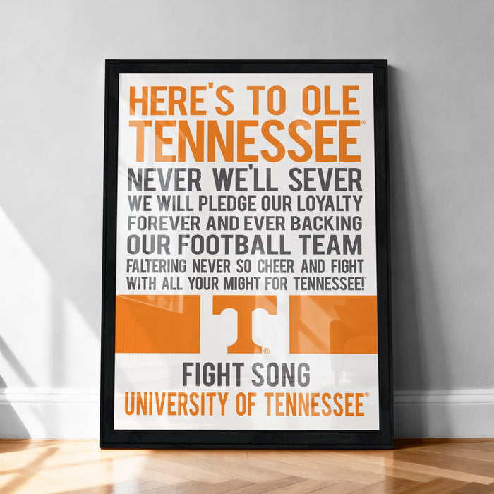The image is a framed poster with text that reads "HERE'S TO OLE TENNESSEE NEVER WELL SEVER WE WILL PEDGE OUR LOYALTY FOREVER AND EVER BACKING OUR FOOTBALL TEAM FALTERING NEVER SO CHEER AND FIGHT WITH ALL YOUR MIGHT FOR TENNESSEE!" The poster is displayed on a wooden floor against a white wall.