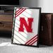 A framed poster with the letter "N" on it is leaning against a wooden cabinet.