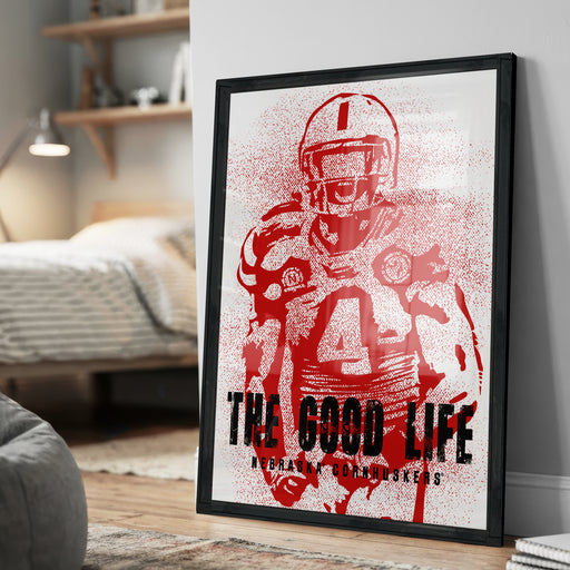 a framed poster of a football player in a red uniform, with the text "THE GOOD LIFE" and "ASKASK CORNHUSKERS" printed on it.