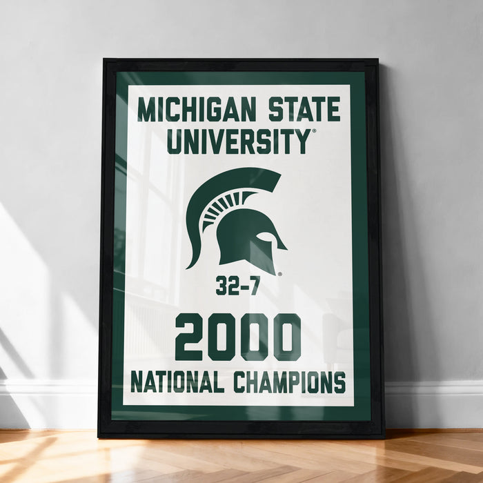 A framed poster celebrating the Michigan State University's 32-7 National Champions, with the university's logo and the year 2000 prominently displayed.