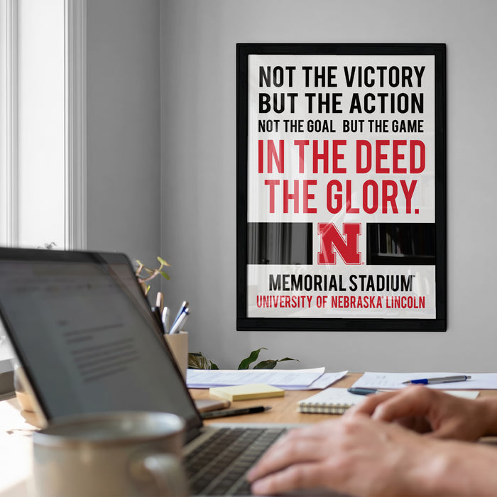 a framed motivational quote on a wall, with a laptop and desk in the foreground.