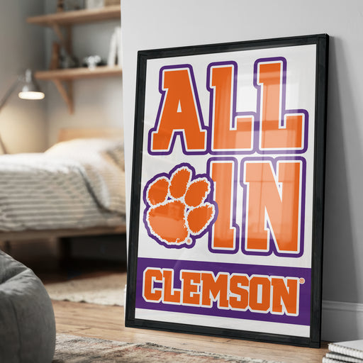 A framed poster with the text "ALL IN CLAMS" and an orange paw print, located in a bedroom setting.