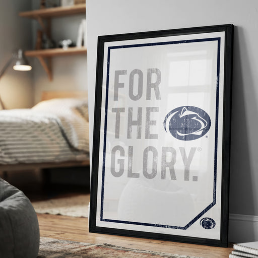 A framed poster with the text "FOR THE GLORY" and a Penn State logo, placed on a wall in a bedroom.