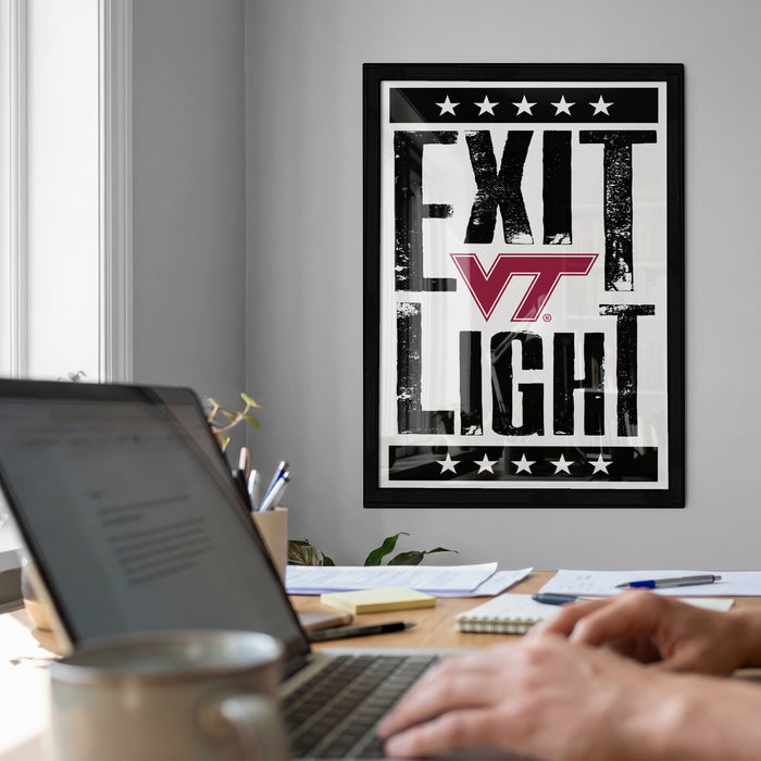 a person working on a laptop at a desk, with a framed poster featuring the text "EXIT LIGHT" in the background.