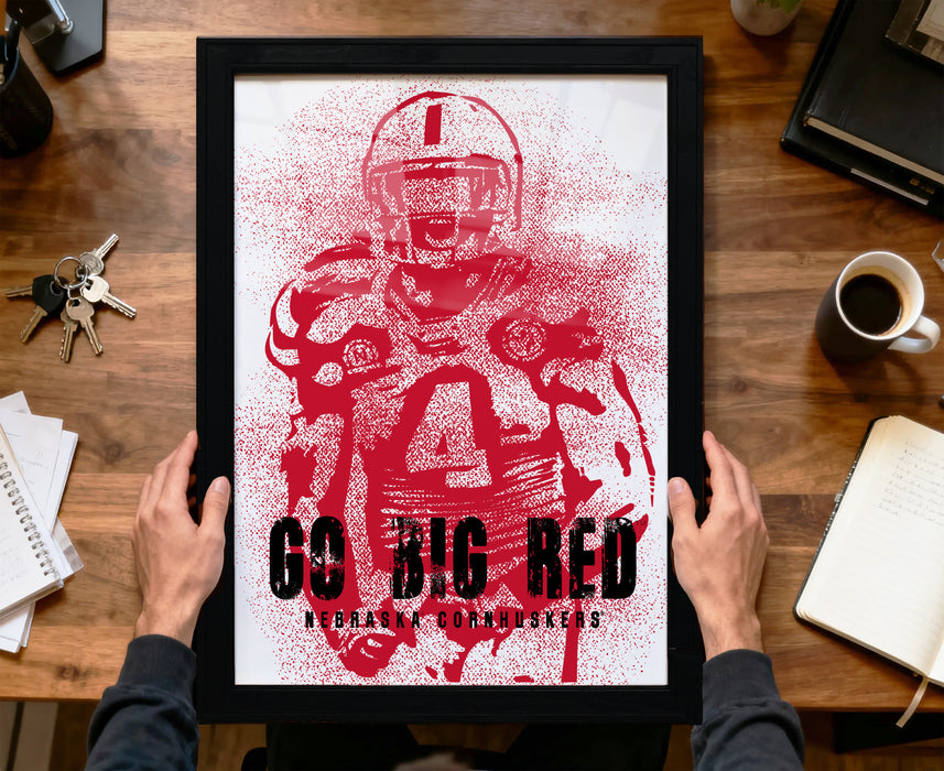 A framed poster featuring a football player in a red uniform, with the text "Go Big Red Nebraska Cornhuskers" printed on it.