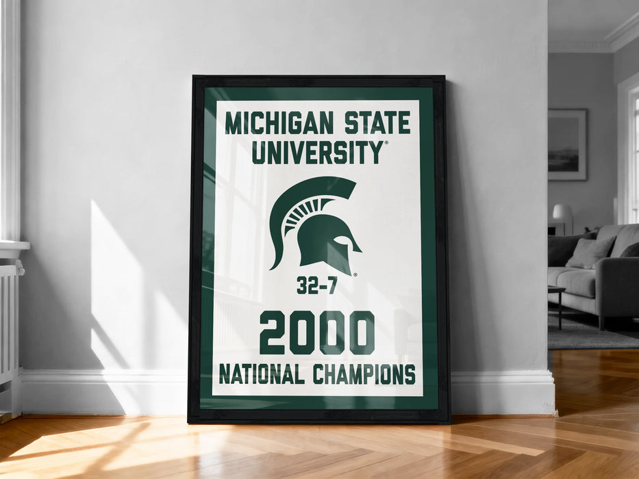 A framed poster celebrating the Michigan State University's 32-7 National Champions, with the text "MICHIGAN STATE UNIVERSITY" and "2000 NATIONAL CHAMPIONS" prominently displayed.