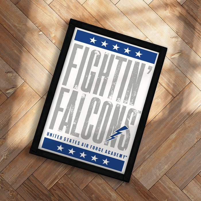a framed poster with the text "FIGHTIN' FALCONS" and a lightning bolt symbol, placed on a wooden floor.