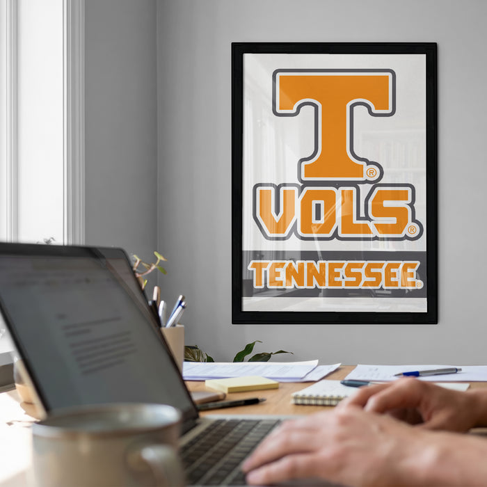 a person working on a laptop at a desk, with a framed poster of the Tennessee State University (TSU) logo in the background.