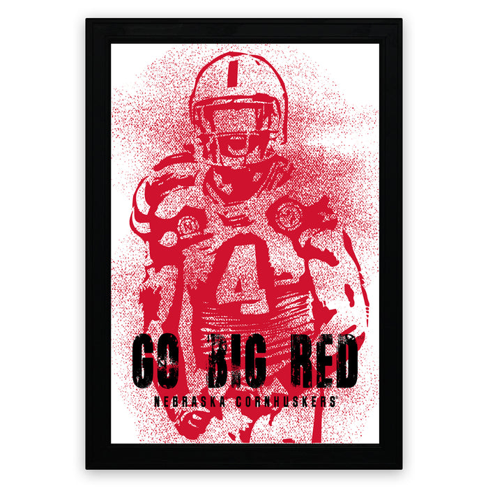 A framed poster featuring a red silhouette of a football player with the text "GO BIG RED" and "NEBRASKA CORHUSKERS" printed on it.
