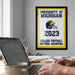 a framed poster of the University of Michigan celebrating the College Football National Champions, with a laptop and a person's hands visible in the foreground.