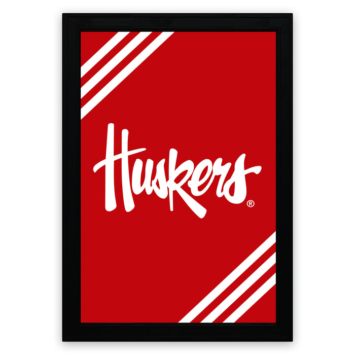 A framed poster with a red background and white diagonal stripes. The poster prominently displays the word "Huskies" in a stylized white font.