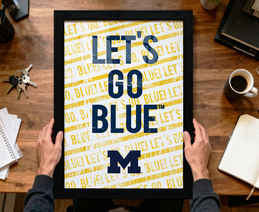 A person is holding up a framed poster with the text "LET'S GO BLUE! LET'S GO BLUE! LET'S GO BLUE! BLUE! BLUE!" printed on it.