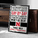 a framed motivational poster with a quote about Nebraska football, placed on a carpeted floor next to a wooden chest.