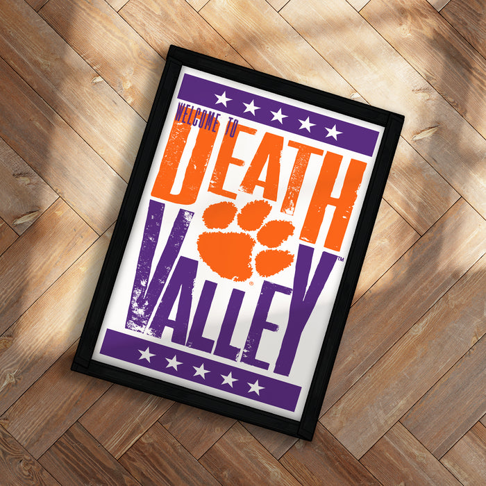 A framed poster with the text "WELCOME TO DEATH VALLEY" and an orange paw print graphic, placed on a wooden floor.