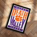 A framed poster with the text "WELCOME TO DEATH VALLEY" and an orange paw print graphic, placed on a wooden floor.