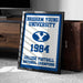 A framed sign displaying the text "BRIGHTAM YOUNG UNIVERSITY" and "COLLEGE FOOTBALL NATIONAL CHAMPIONS" along with a blue and white logo, indicating a celebration of the university's college football national championship victory in 1984.
