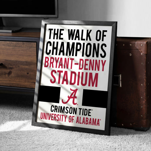 a framed sign that reads "The walk of champions BRYANT-DENNY STADIUM A CRIMSON TIDE UNIVERSITY OF ALABAMA".