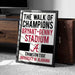 a framed sign that reads "The walk of champions BRYANT-DENNY STADIUM A CRIMSON TIDE UNIVERSITY OF ALABAMA".