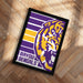 A framed poster featuring the logo of the Louisiana State University Football team, specifically the LSU Tigers.