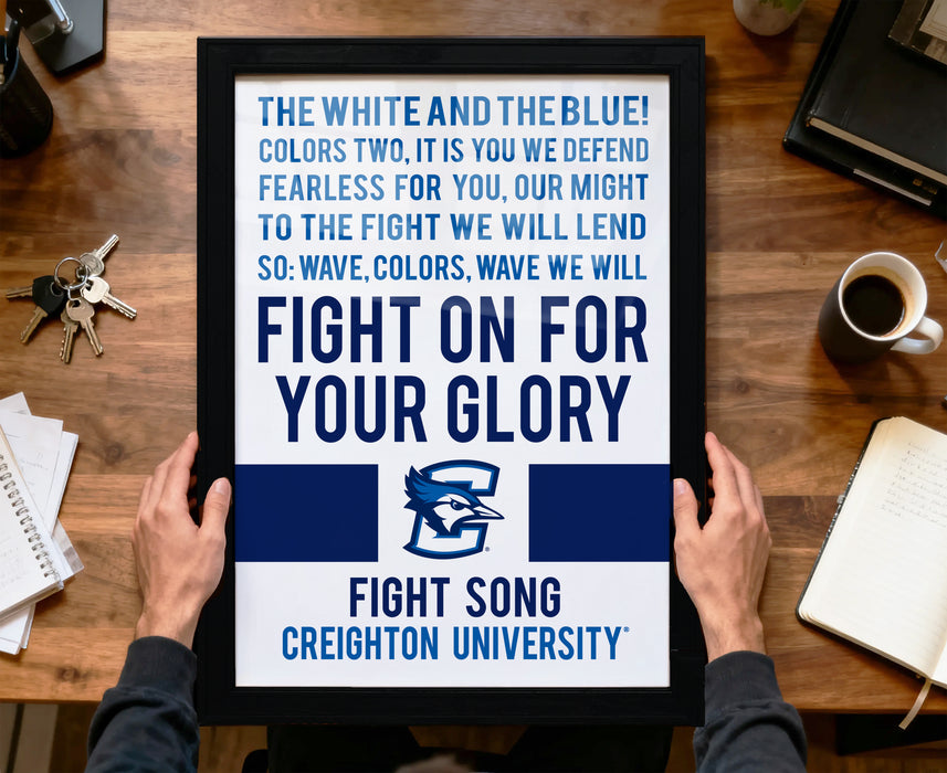 A framed poster with a motivational message is being held by a person's hands, placed on a wooden desk.
