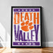 A framed poster with the text "Welcome to Death Valley" and an orange paw print, placed on a wooden floor against a white wall.