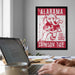 a framed poster of an elephant with the text "ALABAMA" and "CRIMSON TIDE" on it, hanging on a wall above a desk with a laptop and other items.