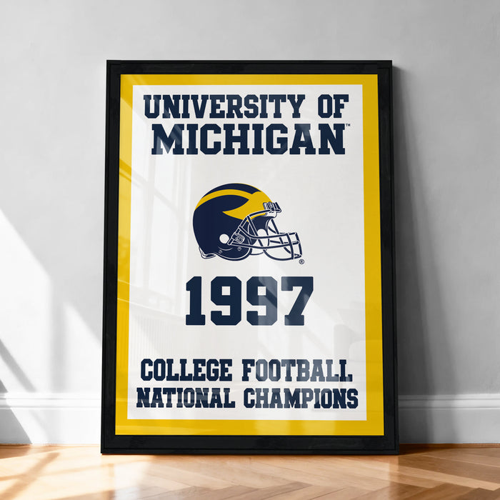 A framed poster with the text "UNIVERSITY OF MICHIGAN 1997 COLLEGE FOOTBALL NATIONAL CHAMPIONS" and a football helmet graphic, indicating that the University of Michigan was a College Football National Champion in 1997.