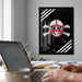 a person working on a laptop at a desk, with a framed poster featuring a skull and crossbones design on the wall behind them.