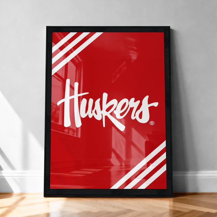 A framed poster with the word "Huskies" written in white cursive text against a red background.