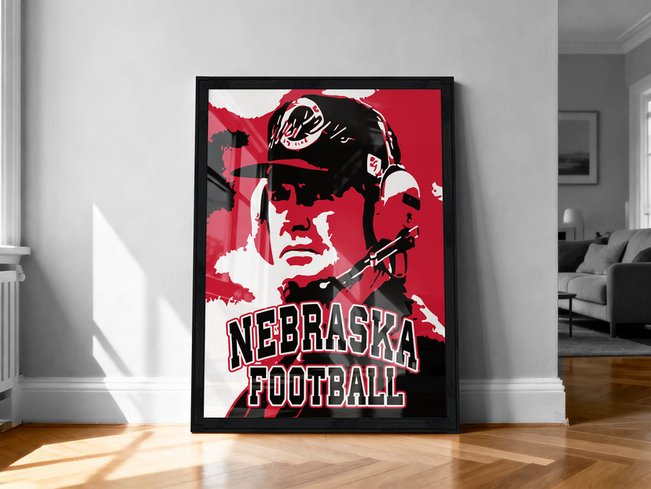 A framed poster of a football coach with the text "NEBRASKA FOOTBALL" on it, displayed on a wall in a room.