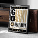 A framed poster with the text "GO ARMY BEAT NAVY" and a military insignia, placed on a carpeted floor next to a wooden chest.