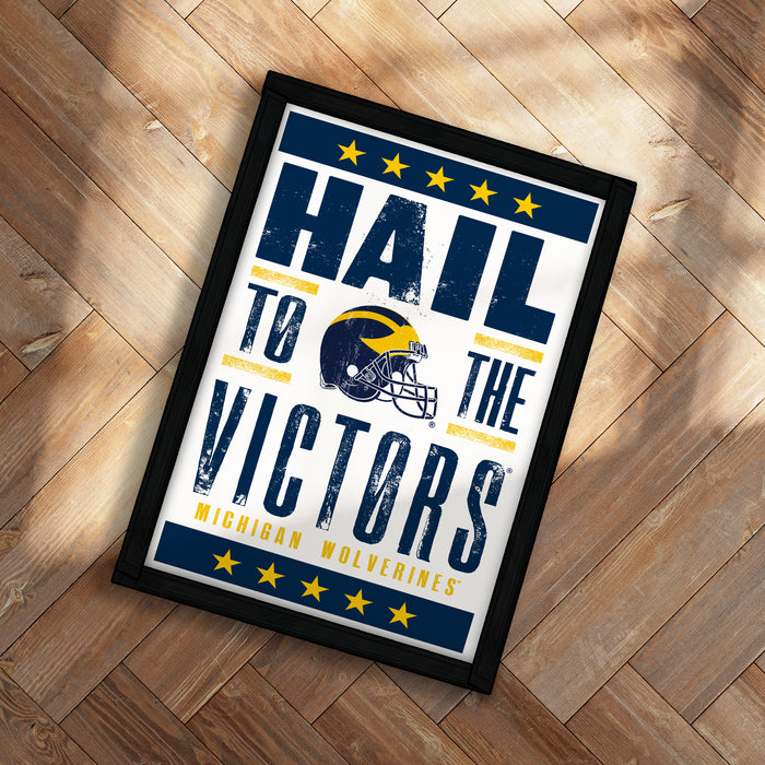 A framed poster with the text "Hail to the Victors" and a football helmet graphic, representing the Michigan Wolverines football team.