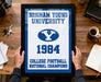 A framed poster with the text "BRIGHTAM YOUNG UNIVERSITY" and "COLLEGE FOOTBALL NATIONAL CHAMPIONS" is being held by a person's hands.