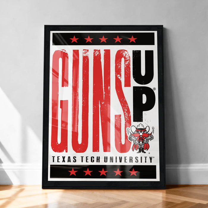 A framed poster with the text "GUNS UP" prominently displayed, along with a graphic of a character wearing a gun. The poster is set against a white wall and has a black border.