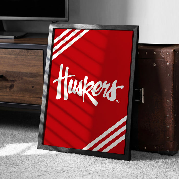 A framed poster with the word "Huskies" written on it, placed on a carpeted floor next to a wooden chest.