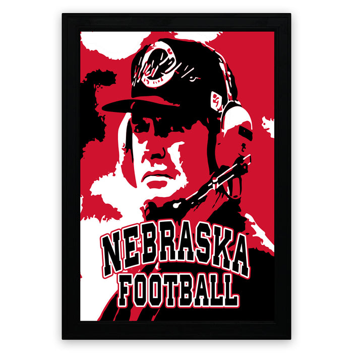 A framed poster featuring a close-up portrait of a person wearing a baseball cap and the text "NEBRASKA FOOTBALL" in bold letters.