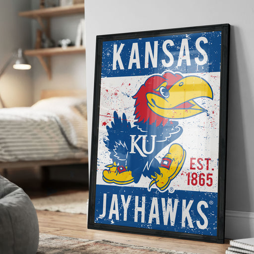A framed poster of the Kansas Jayhawks, a sports team, is displayed on a wall in a room.