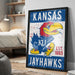 A framed poster of the Kansas Jayhawks, a sports team, is displayed on a wall in a room.