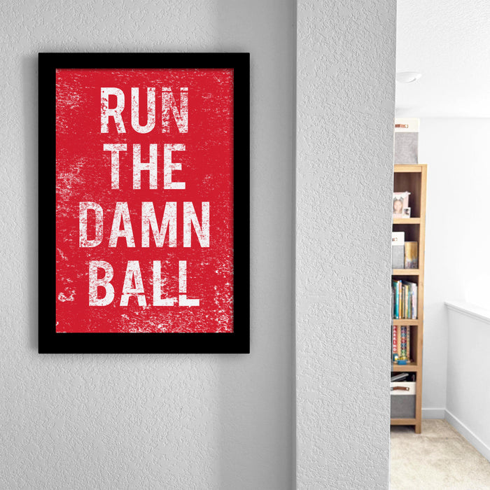 a framed poster with the text "RUN THE DAMN BALL" in white letters against a red background.