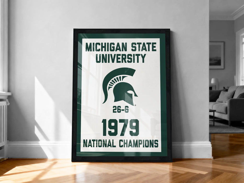 A framed poster on a wall celebrating the Michigan State University's 1979 National Champions, featuring the university's logo and the text "Michigan State University 1976-1979 NATIONAL CHAMPIONS".