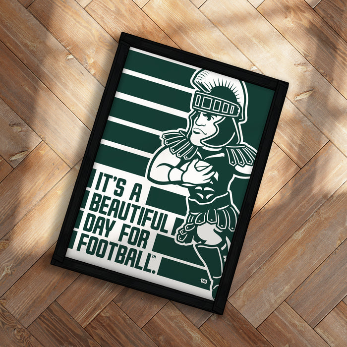 A framed poster featuring a cartoon character in a green and white color scheme, with the text "It's a beautiful day for football!" displayed on the poster.