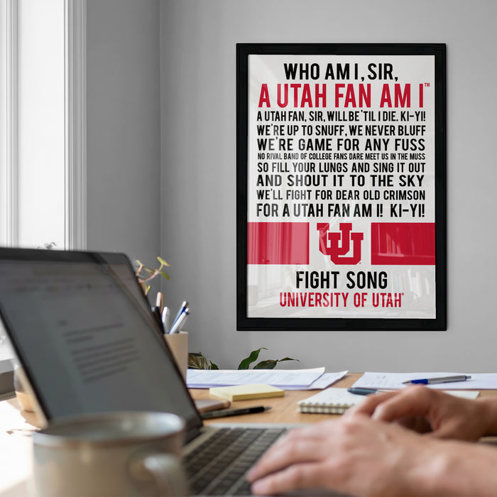 a framed poster with text on it, hanging on a wall next to a laptop.