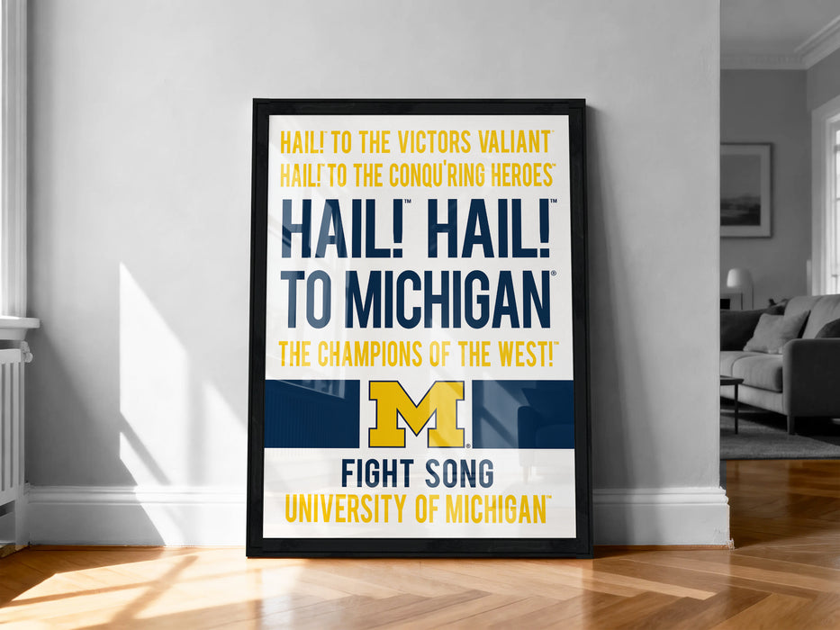a framed poster with text that reads "Hail! To the victors! Valiant! Hail! To the conouring heroes! Hail! To Michigan! The champions of the west! Fight Song University of Michigan!"
