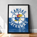 A framed poster featuring the Kansas Jayhawks logo, a bird with a yellow beak and red head, against a blue background with a white dotted pattern.