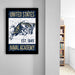 a framed poster of a naval emblem hanging on a wall, with a bookshelf visible in the background.